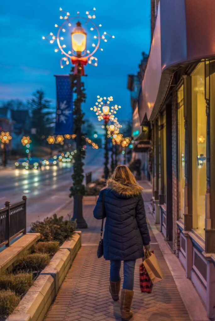 woman walks down a street with retail shops